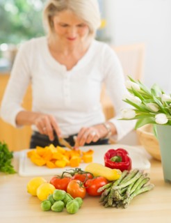 Portrait of senior woman cutting vegetables in kitchen.