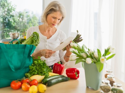 Portrait of senior woman with shopping bag in kitchen.