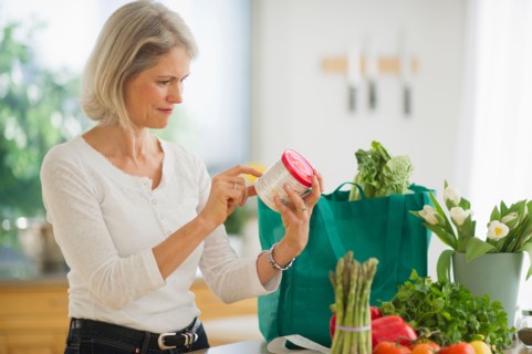 Portrait of senior woman checking product in kitchen.
