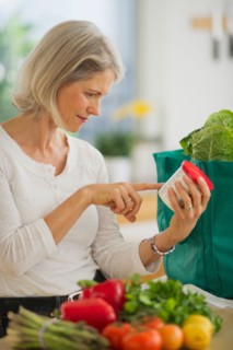 Portrait of senior woman checking product in kitchen.