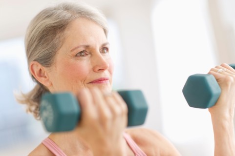 Portrait of senior woman exercising with dumbbells in gym.