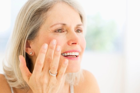 Portrait of senior woman applying moisturizer.