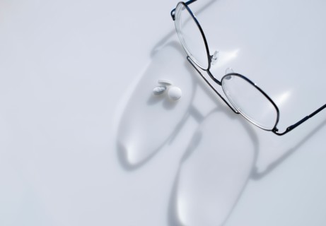 Close up of glasses and pills on white background, studio shot.
