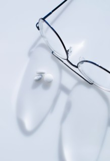 Close up of glasses and pills on white background, studio shot.