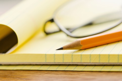 Close up of glasses, notebook and pencil, studio shot.