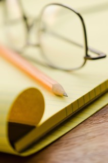 Close up of glasses, notebook and pencil, studio shot.