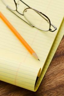 Close up of glasses, notebook and pencil, studio shot.