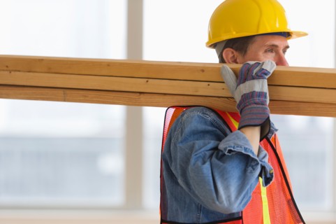 Construction worker carrying planks.