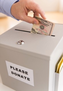 Man's hand putting dollars into donation box.