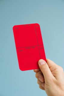 Close up of man's hand showing red card, studio shot.