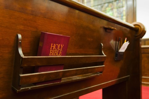 Close up of bible on wooden church pew.