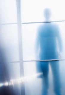 Silhouettes of businessman behind glass door.