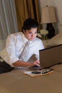 Businessman working on laptop in hotel room.