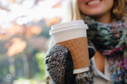 Woman wearing gloves holding coffee cup. Photo : Jamie Grill