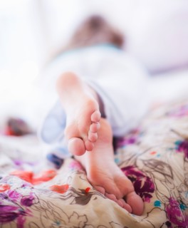 Close-up of woman's feet lying on bed. Photo : Daniel Grill