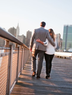 USA, New York, Long Island City, Rear view of young couple walking on boardwalk, Manhattan skyline