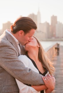 USA, New York, Long Island City, Young couple kissing on boardwalk, Manhattan skyline in background