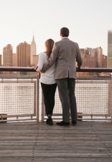 USA, New York, Long Island City, Rear view of young couple standing on boardwalk, Manhattan skyline