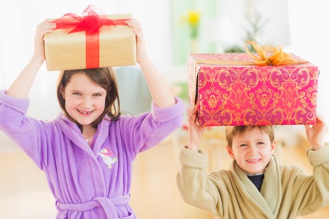Girl (8-9) and boy (6-7) carrying christmas gifts on their heads. Photo : Daniel Grill