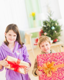 Girl (8-9) and boy (6-7) holding christmas gifts. Photo : Daniel Grill