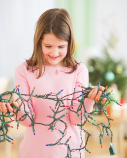 Portrait of girl (8-9) with christmas lights. Photo : Daniel Grill
