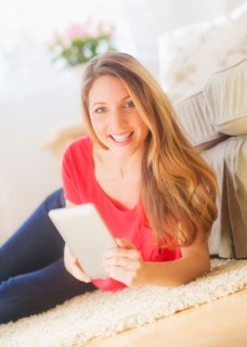 Portrait of young woman working with digital tablet in living room. Photo : Daniel Grill