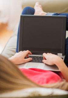 Portrait of young woman with laptop in living room. Photo : Daniel Grill