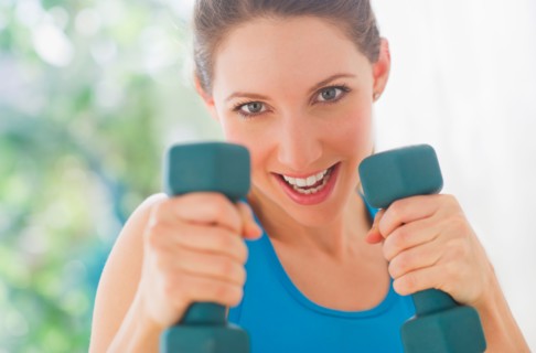 Portrait of young woman with dumbbells. Photo : Daniel Grill