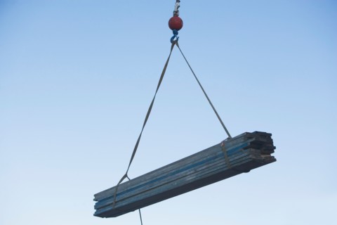 Mid-air view at crane's hook lifting wooden planks. Photo : fotog