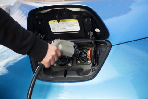 Close-up of man charging electric car. Photo : fotog