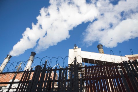 low angle view of factory chimneys behind fence. Photo : fotog