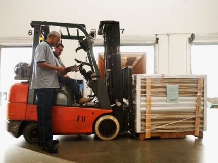 Warehouse workers talking by forklift truck.