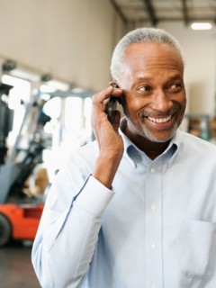 Businessman using phone in warehouse.