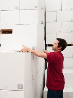 Worker stacking boxes in warehouse.