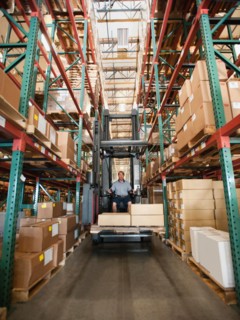 Forklift truck stacking boxes in warehouse.