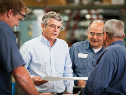 Businessman and workers talking in factory.