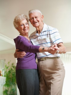Senior couple dancing at home.