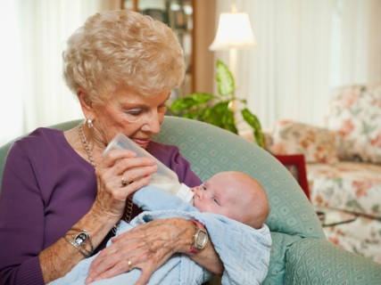 Senior woman giving milk to grandson (2-5 months).
