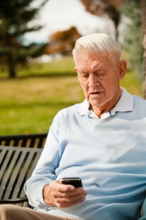 Senior man using phone in park.