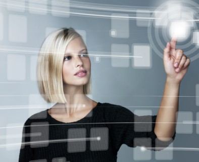 Young woman using futuristic touchscreen, studio shot. Photo : Yuri Arcurs