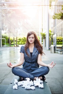 USA, Seattle, Young businesswoman meditating in front of crumbled paper balls. Photo : Take A Pix