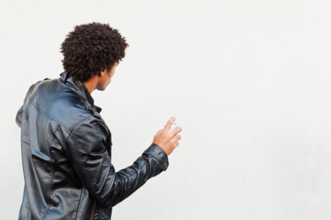 Man holding spray paint against white wall, studio shot. Photo : Sarah M. Golonka
