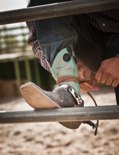 Close-up of cowboy tying shoe. Photo : Mike Kemp