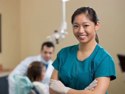 Portrait of dentist, dentist and patient in background. Photo : Dan Bannister