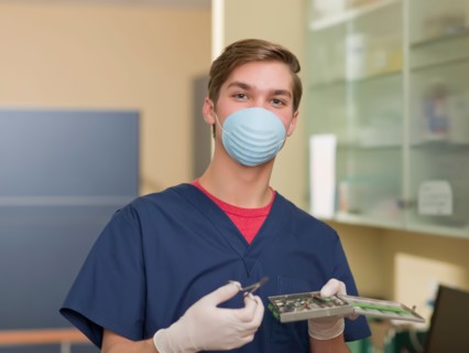 Portrait of dentist holding dental tools. Photo : Dan Bannister