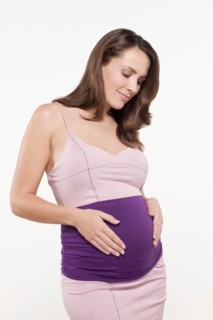 Portrait of pregnant woman in pink dress, studio shot. Photo : Jan Scherders