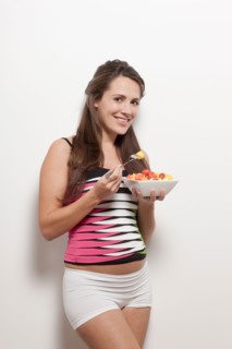 Portrait of pregnant woman holding bowl with salad, studio shot. Photo : Jan Scherders