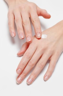 Close up of woman's hands applying moisturizer, studio shot. Photo : Jan Scherders