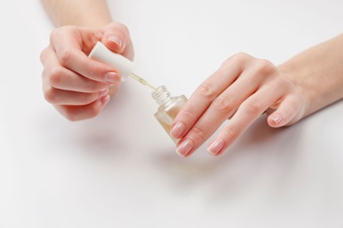Close up of woman's hands holding nail polish, studio shot. Photo : Jan Scherders