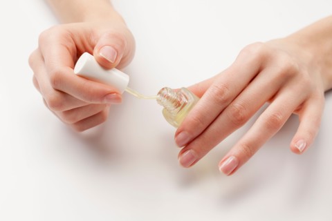 Close up of woman's hands holding nail polish, studio shot. Photo : Jan Scherders
